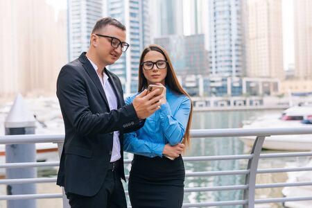 Portrait of businessman and business womanlooking at technology with interest on the skyscraper on backgroundの写真素材