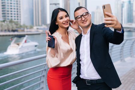 Business man and woman talking in urban city center in business style working together taking selfie on the phoneの写真素材