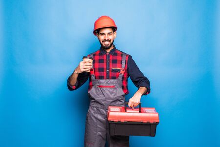 Portrait of indian happy man holding a red tool box isolated on blue backgroundの写真素材