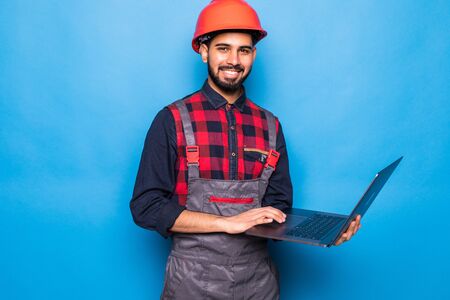 Indian beard repairman using laptop against blue backgroundの写真素材