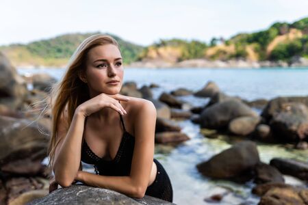 Attractive woman in bikini posing near rocks on amazing landscape