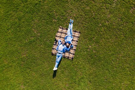 Happy couple in love lying in the park together on blanket from aboveの写真素材