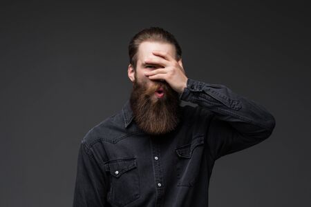 Young man with hand on face covering eyes for surprise standing over isolated gray background .の写真素材