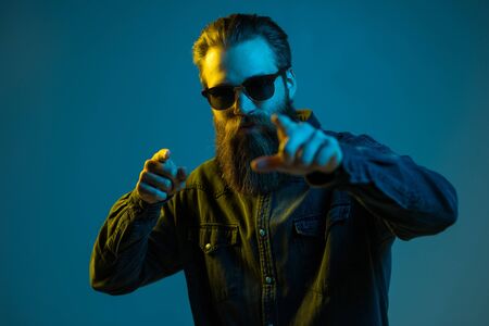 Young hipster bearded man wearing sunglasses on yellow background