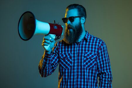 Fashion portrait of emotional hipster man with megaphone on white background in stylish sunglasses. Sales man using megaphone yellingの写真素材