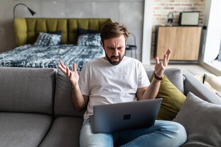 Outraged angry man reading bad news, looking at screen, having problem with broken laptopの写真素材