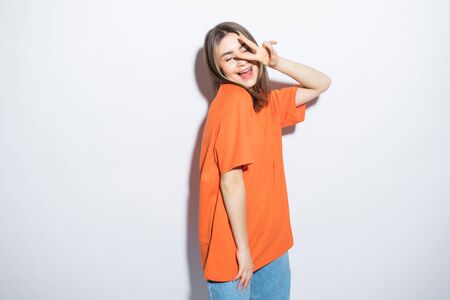 beautiful happy cute smiling woman showing peace sign in casual clothes with red lips isolated on whiteの写真素材