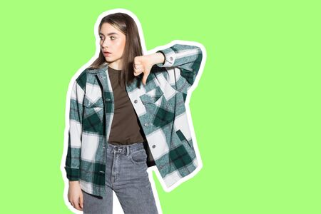 Collage in magazine style with colorful girl with thumbs down on green backgroundの写真素材