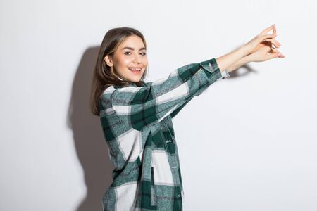 Happy young woman in a plaid shirt with arms raised upの写真素材