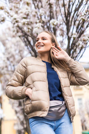 Young woman near blossom tree outdoors in spring day