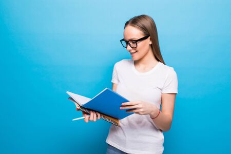 Beautiful smart young girl reading book isolated on the blue background