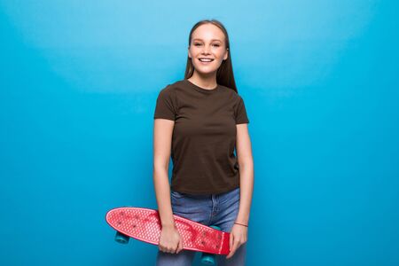 Portrait of woman posing with skateboard on blue backgroundの写真素材