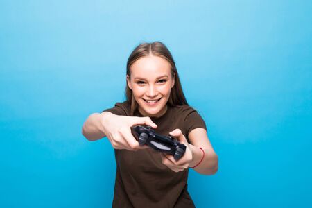 Portrait of girl playing video game on weekend isolated on blue backgroundの写真素材