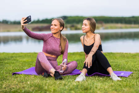 Beautiful girls taking a selfie with a smart phone before going for a run outdoors