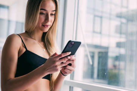 Glad, smiling and young woman lying on floor at fitness mat and using laptop computer resting after...