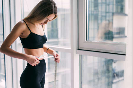 Glad, smiling and young woman lying on floor at fitness mat and using laptop computer resting after trainingの写真素材