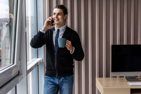 Young man looking out his window at home in the kitchen