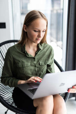 Businesswoman working at office desk and texting with her mobile phone