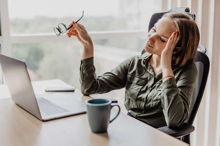 Businesswoman working at office desk and texting with her mobile phone