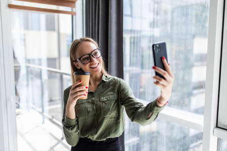 Businesswoman working at office desk and texting with her mobile phone