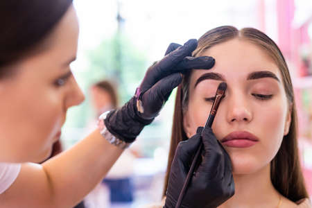 Woman correcting eyebrows form in salon by artistの写真素材