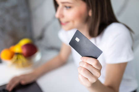 Smiling woman online shopping using laptop and credit card in kitchen