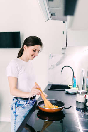 The joyful beautiful woman is on the kitchen prepares to eat