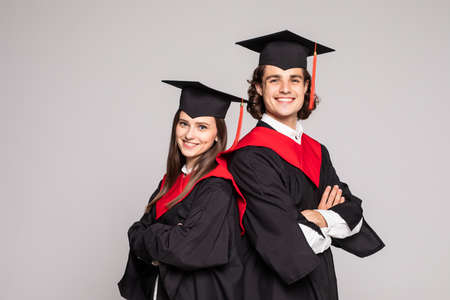 Portrait of two happy graduating students over white background.の写真素材