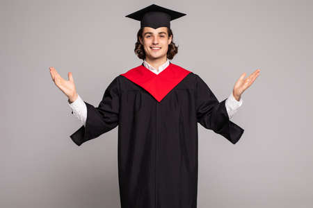 Young handsome graduated man with long hair over isolated background crazy and mad shouting and yelling with aggressive expression and arms raised. Frustration concept.の写真素材