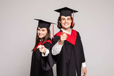 Two graduate couple pointed on camera isolated on white backgroundの写真素材