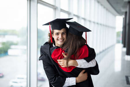A graduates in the mantle embrace and enjoy. Beautiful graduate girl and boy enjoyed the ceremony graduation.の写真素材