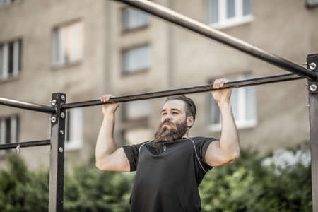 Young man doing pull-up on horizontal bar. Mans fitness at the stadiumの写真素材