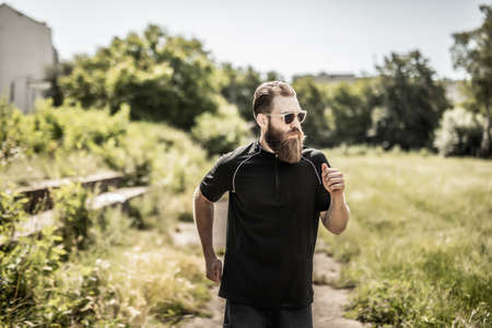 bearded man running a cross in the park at green fence