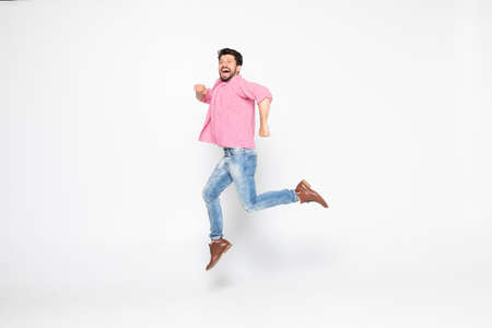 Excited young man jumping and smiling isolated