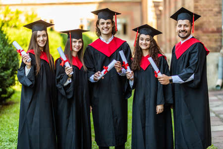 Close-up of five graduates posing in front of the universityの写真素材