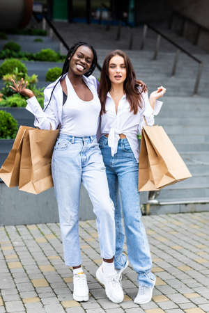 Two african and caucasian female friends on vacation shopping outdoorsの写真素材