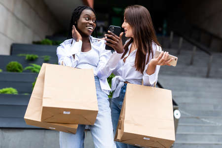 shopping and tourism concept - beautiful girls with shopping bags in ctiy