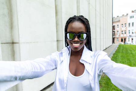 Selfie portrait of laughing black woman outside with curly hairの写真素材