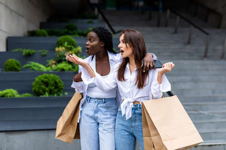 shopping and tourism concept - beautiful girls with shopping bags in ctiyの写真素材