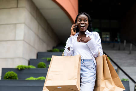 Young woman at the street with shopping bags talking on mobile phoneの写真素材