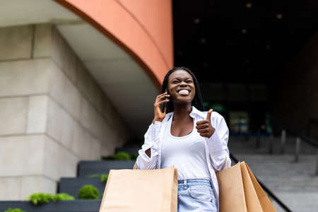 young woman talking on the phone with shopping bagsの写真素材