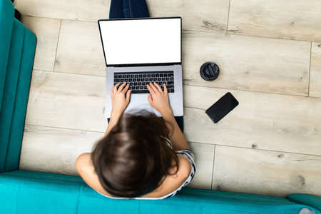 Top view of a female student relaxes sitting on a wooden floor at home and chooses suitable online...