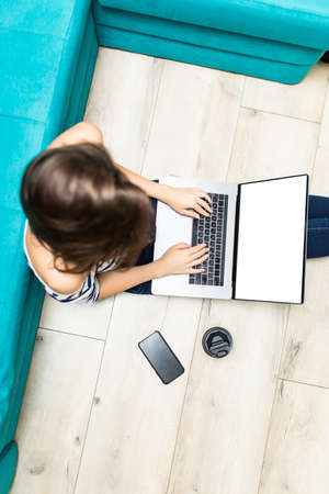Top view of a female student relaxes sitting on a wooden floor at home and chooses suitable online courses.の写真素材