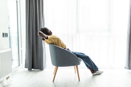 Happy african girl relaxing holding hands sit on chair at home