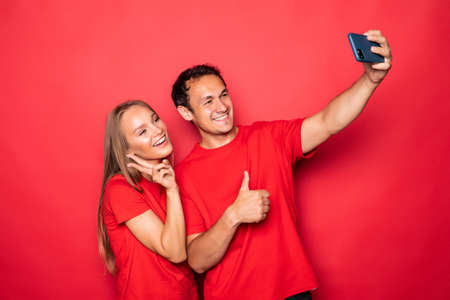 Couple take selfie on phone isolated on red backgroundの写真素材