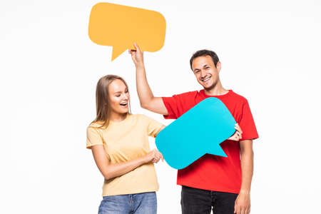 Portrait of a happy young couple holding empty speech bubbles over white backgroundの写真素材