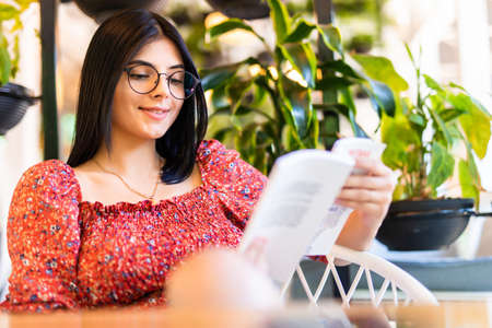 woman reading book at cafe near window