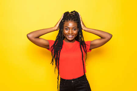 Young african american girl with hands over head standing over yellow background.の写真素材