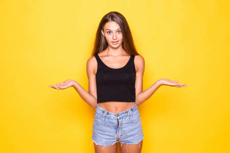 Young woman having doubts with confuse face expression over yellow backgroundの写真素材