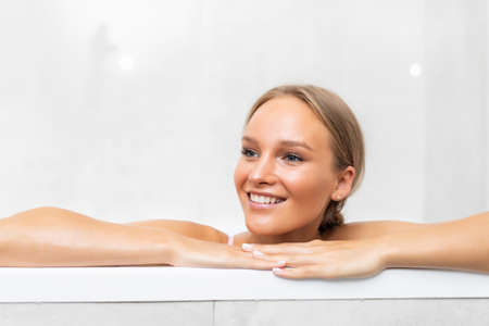 Portrait of young woman laying in bathtub and looking on copy space